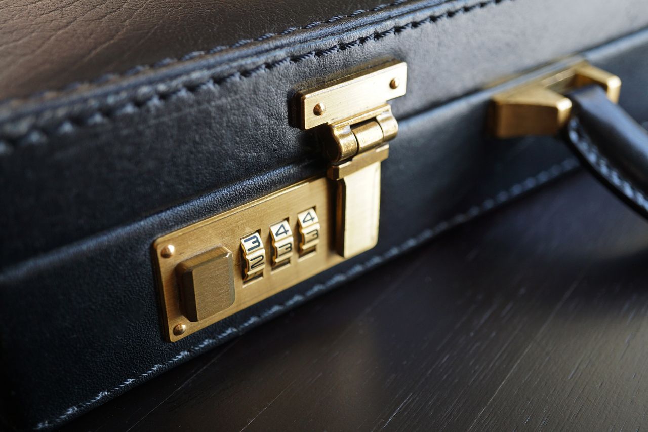 creative-02 Close-up of a black leather briefcase with a brass combination lock for business security.
